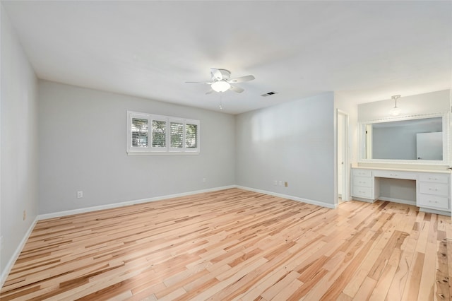 unfurnished bedroom with ceiling fan, built in desk, and light hardwood / wood-style floors