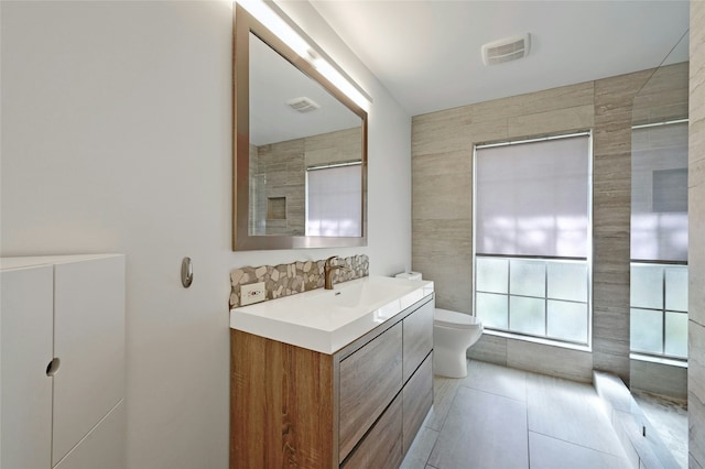 bathroom with vanity, tile walls, tile patterned floors, and toilet