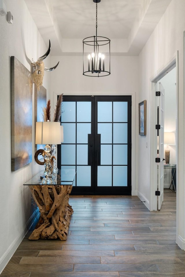 entryway featuring hardwood / wood-style floors, a raised ceiling, and a chandelier