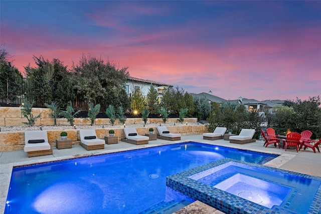 pool at dusk with an in ground hot tub and a patio