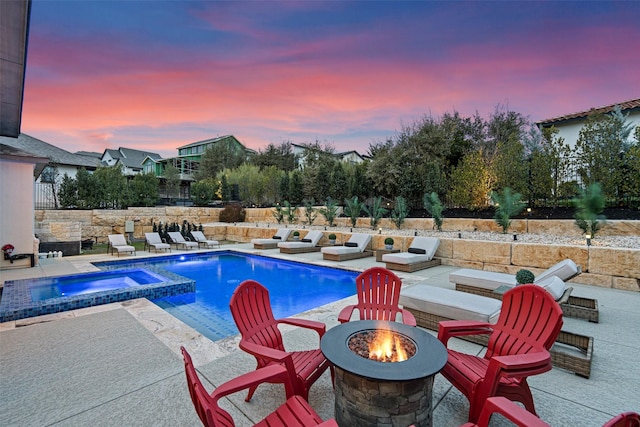 pool at dusk with a patio area, an in ground hot tub, and an outdoor fire pit