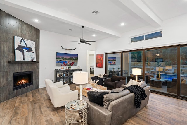 living room with beam ceiling, a tile fireplace, ceiling fan, and hardwood / wood-style flooring