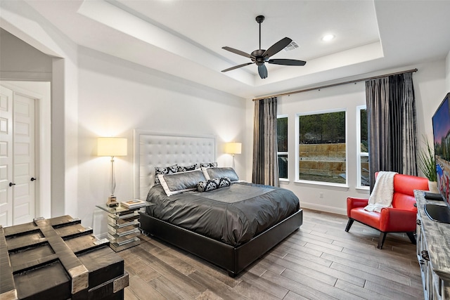 bedroom featuring hardwood / wood-style flooring, ceiling fan, and a tray ceiling