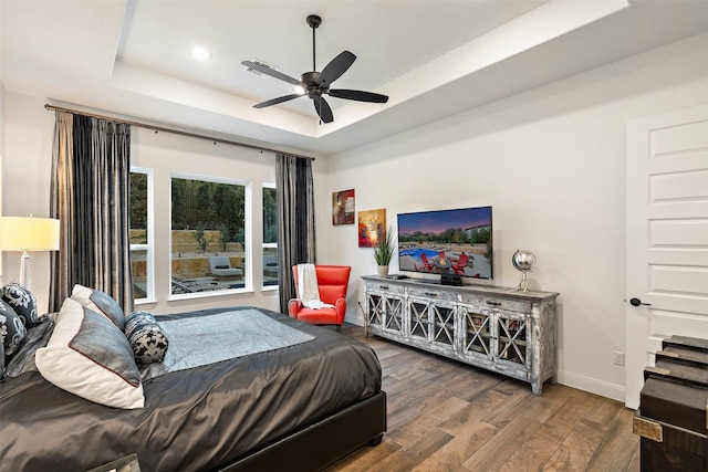 bedroom featuring ceiling fan, dark hardwood / wood-style floors, and a raised ceiling