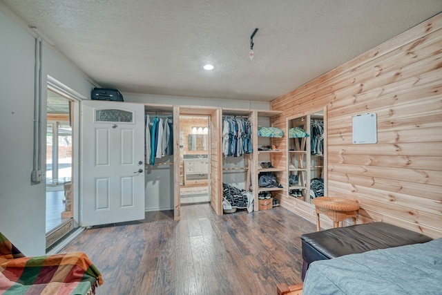 bedroom featuring ensuite bath, wood-type flooring, a textured ceiling, a closet, and log walls