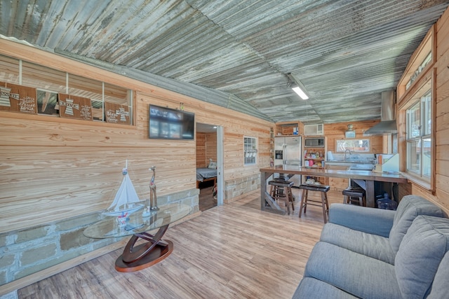 living room with lofted ceiling, sink, wood ceiling, wood-type flooring, and wooden walls