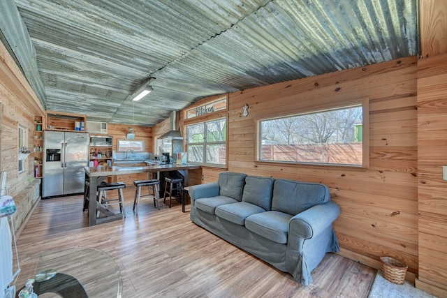 living room featuring lofted ceiling, light hardwood / wood-style floors, and wood walls