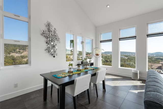 dining room featuring dark tile patterned floors, a mountain view, and high vaulted ceiling