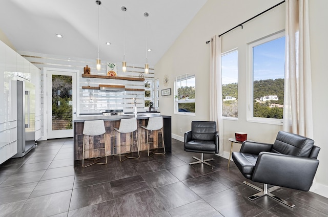 kitchen featuring pendant lighting, lofted ceiling, high end refrigerator, a kitchen breakfast bar, and a kitchen island with sink