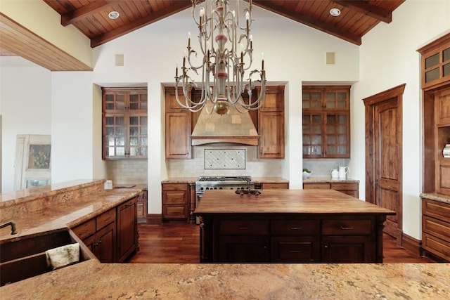 kitchen featuring butcher block countertops, wooden ceiling, a sink, and a center island