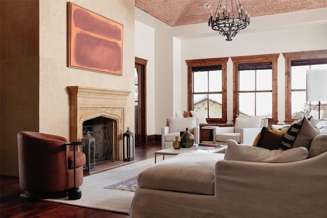 living room featuring a premium fireplace, wood finished floors, baseboards, brick ceiling, and an inviting chandelier