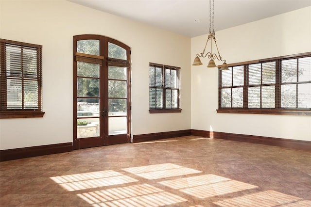 unfurnished room with baseboards, french doors, and a healthy amount of sunlight