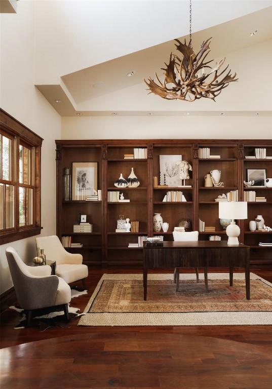 living area featuring a high ceiling, an inviting chandelier, and wood finished floors