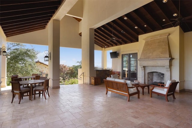 view of patio with outdoor dining space, french doors, ceiling fan, and an outdoor living space with a fireplace