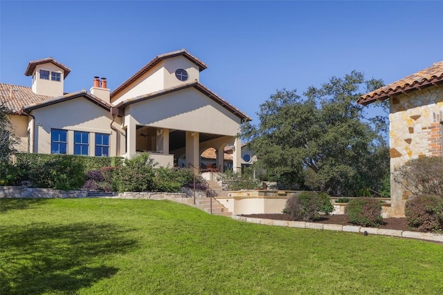 exterior space featuring a yard, a chimney, a tiled roof, and stucco siding