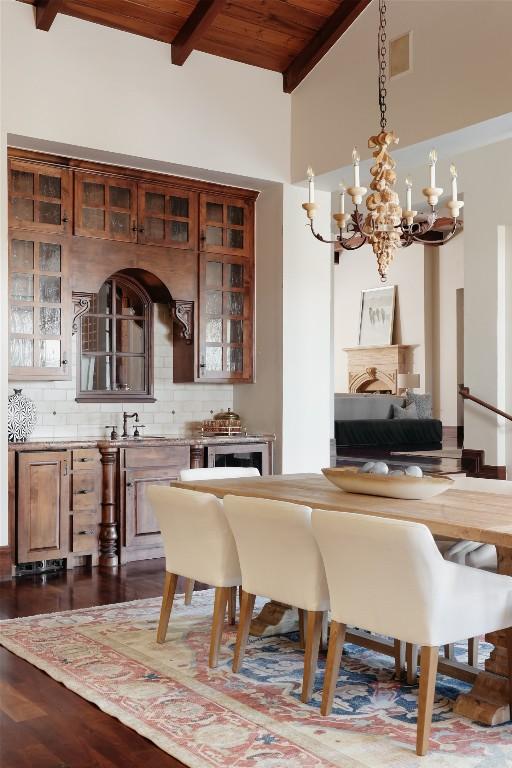 dining room with wooden ceiling, dark wood finished floors, beam ceiling, and a notable chandelier