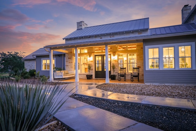 back house at dusk featuring covered porch