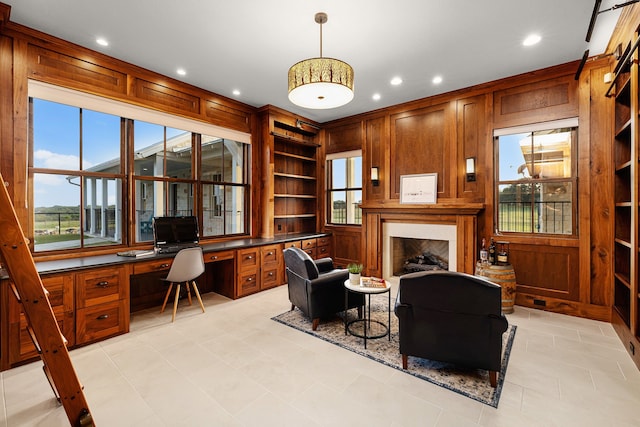 home office featuring a healthy amount of sunlight, built in desk, built in features, and wood walls