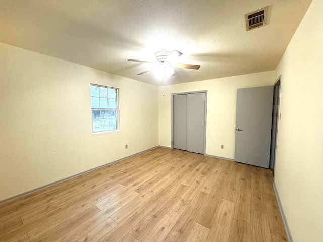 unfurnished bedroom with ceiling fan, visible vents, light wood-type flooring, baseboards, and a closet