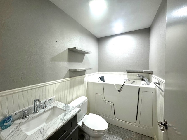 bathroom with a garden tub, tile patterned flooring, vanity, toilet, and a textured wall