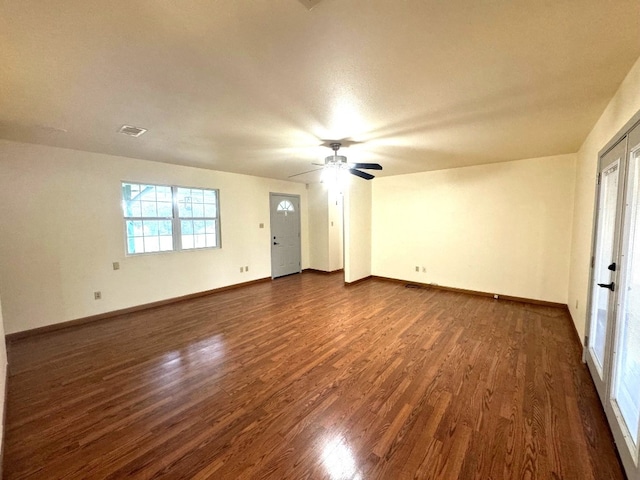 unfurnished living room featuring baseboards, ceiling fan, visible vents, and dark wood-type flooring