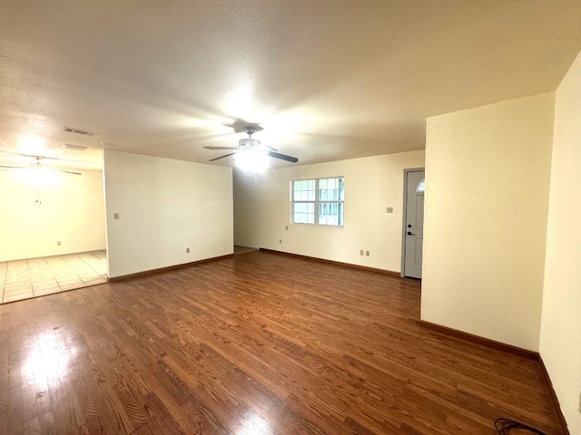empty room featuring visible vents, a ceiling fan, baseboards, and wood finished floors