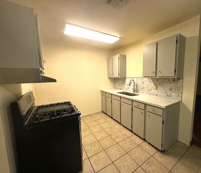 kitchen with a sink, gas range, light tile patterned floors, tasteful backsplash, and visible vents