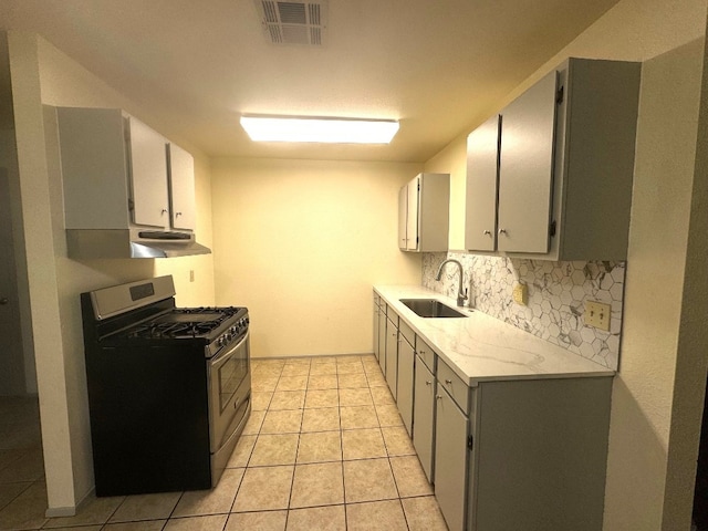 kitchen with visible vents, decorative backsplash, light tile patterned flooring, gas range, and a sink