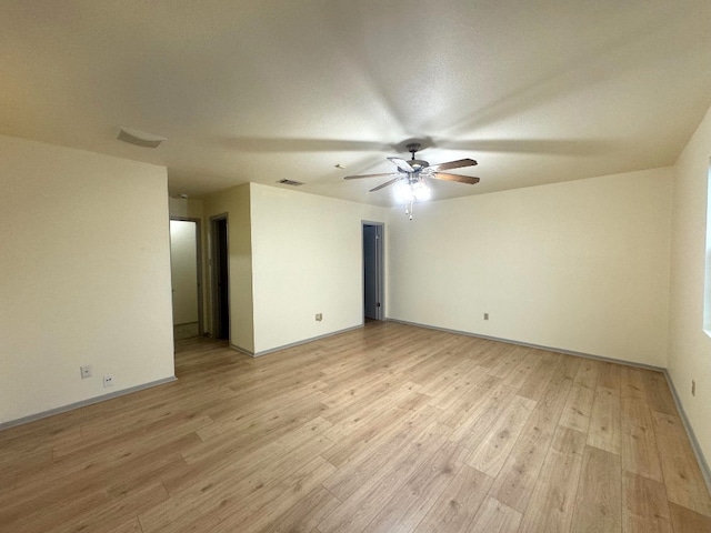 empty room with baseboards, a ceiling fan, light wood-type flooring, and visible vents