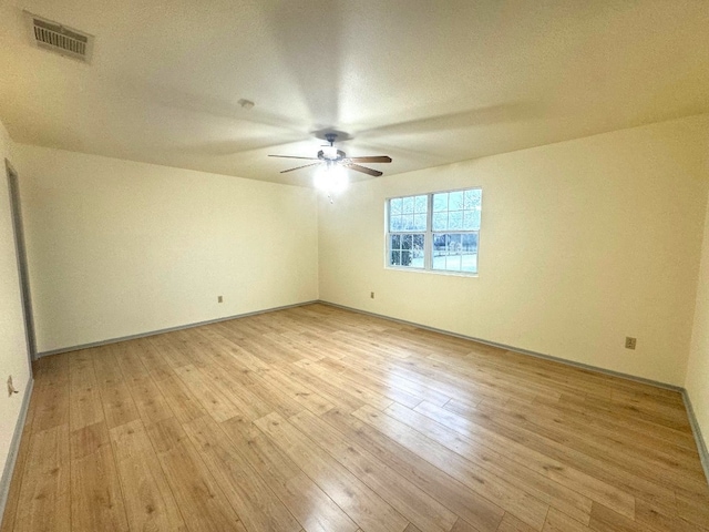 empty room with visible vents, light wood-style flooring, ceiling fan, and baseboards