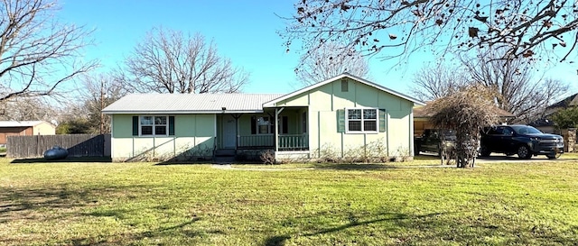 view of front of house featuring a front lawn, fence, covered porch, and metal roof