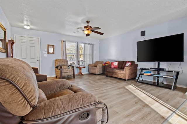 living room with ceiling fan, light hardwood / wood-style flooring, and a textured ceiling