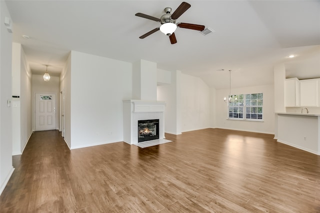 unfurnished living room featuring lofted ceiling, sink, ceiling fan with notable chandelier, and hardwood / wood-style flooring