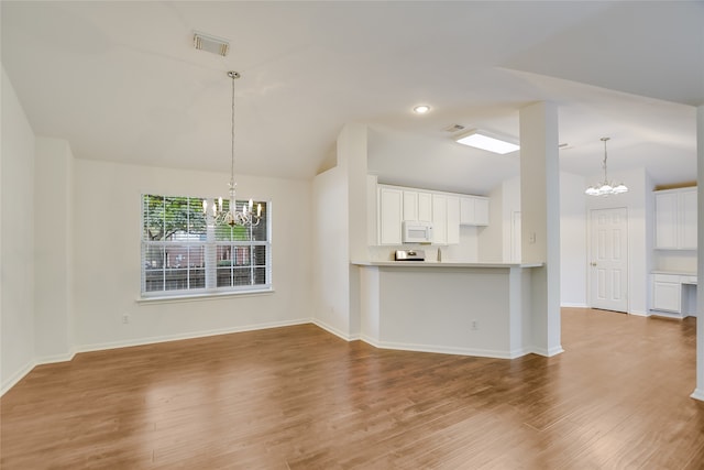 unfurnished living room with an inviting chandelier, vaulted ceiling, and light hardwood / wood-style flooring