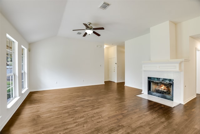 unfurnished living room with a tiled fireplace, vaulted ceiling, dark wood-type flooring, and ceiling fan