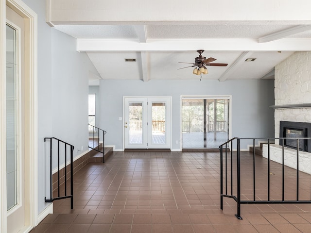 interior space with lofted ceiling with beams, a stone fireplace, and ceiling fan