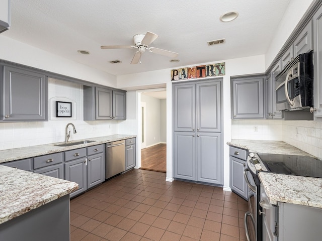 kitchen with visible vents, appliances with stainless steel finishes, a sink, and gray cabinetry