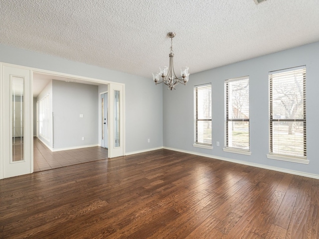 unfurnished room featuring a notable chandelier, baseboards, dark wood-style flooring, and french doors