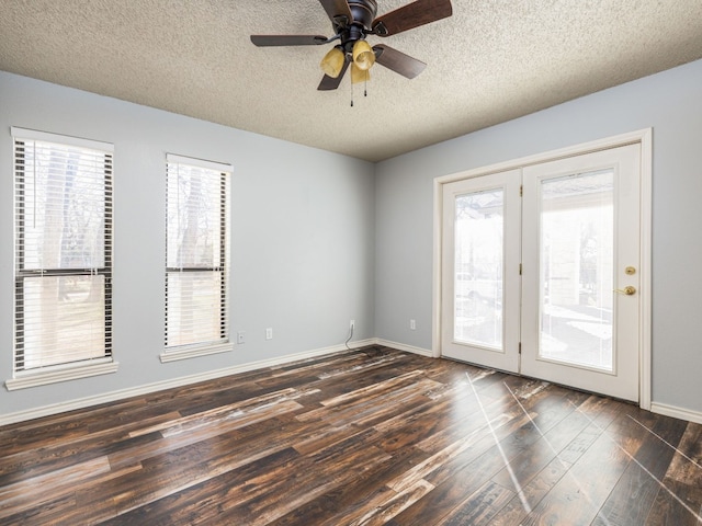 empty room featuring dark wood-style floors, ceiling fan, baseboards, and a textured ceiling