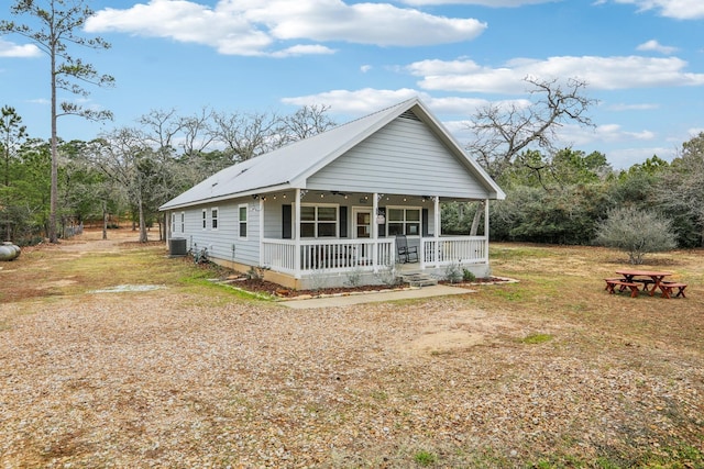 view of front of house featuring central AC, covered porch, and a front lawn