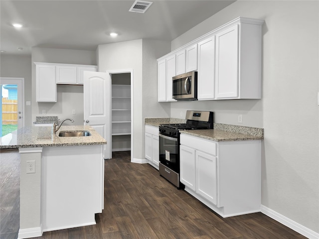 kitchen with appliances with stainless steel finishes, sink, a center island with sink, and white cabinets