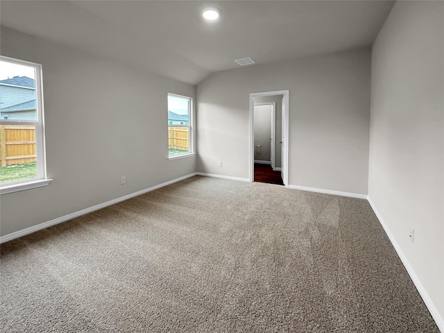 spare room with lofted ceiling and dark colored carpet