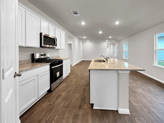 kitchen featuring dark wood-type flooring, sink, appliances with stainless steel finishes, an island with sink, and white cabinets