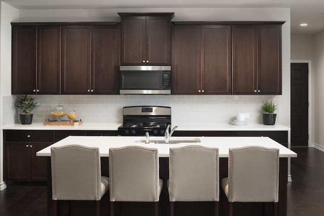 kitchen featuring appliances with stainless steel finishes, sink, backsplash, and a kitchen breakfast bar