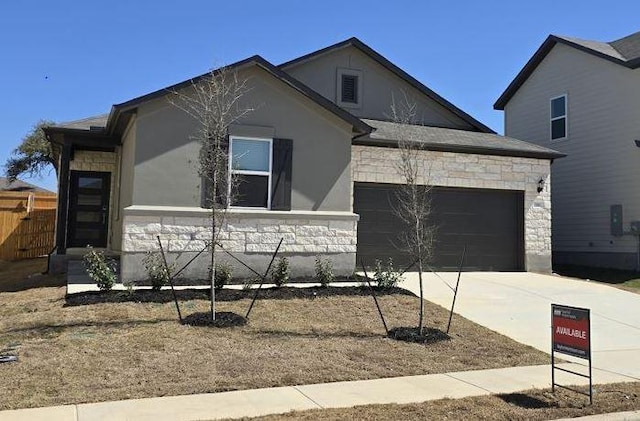 view of front of property with stone siding, an attached garage, and driveway