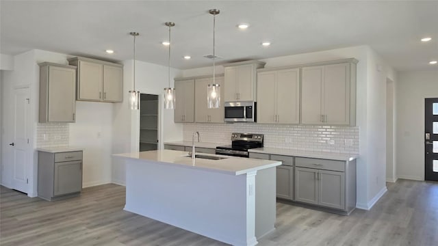 kitchen featuring light wood finished floors, light countertops, gray cabinets, stainless steel appliances, and a sink