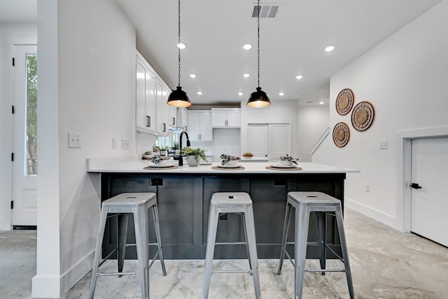 kitchen featuring white cabinetry, decorative light fixtures, kitchen peninsula, and a breakfast bar