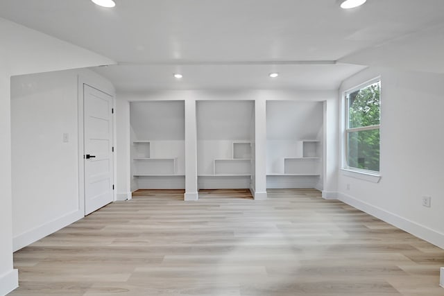 bonus room with light hardwood / wood-style flooring, built in shelves, and vaulted ceiling