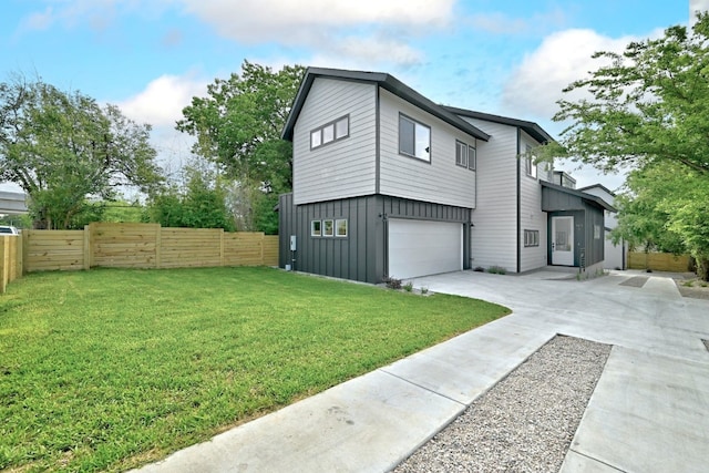 view of side of home featuring concrete driveway, a lawn, an attached garage, board and batten siding, and fence