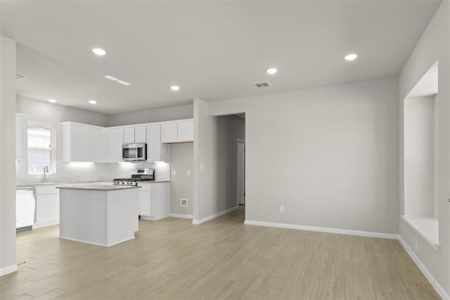 kitchen featuring tasteful backsplash, appliances with stainless steel finishes, a kitchen island, and white cabinets